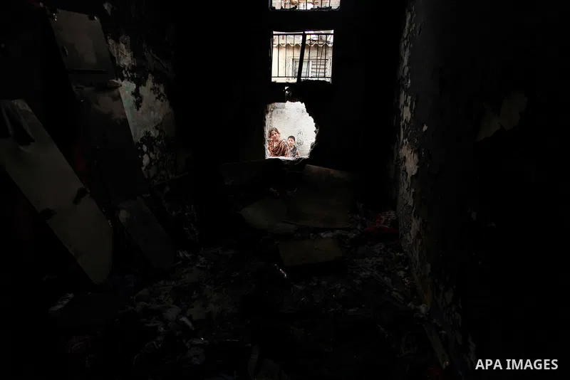 Palestinian children look through the window of burnt house after a candle caused a fire at the al-Hendi family's home at the al-Shati refugee camp in Gaza City on May 7, 2016. Photo by Ashraf Amra