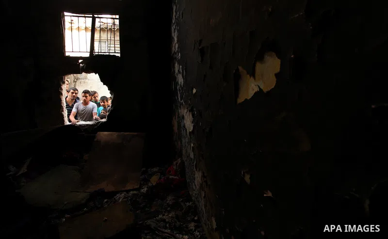 Palestinian children look through the window of burnt house after a candle caused a fire at the al-Hendi family's home at the al-Shati refugee camp in Gaza City on May 7, 2016. Photo by Ashraf Amra