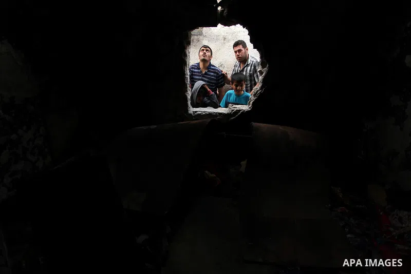 Palestinian children look through the window of burnt house after a candle caused a fire at the al-Hendi family's home at the al-Shati refugee camp in Gaza City on May 7, 2016. Photo by Ashraf Amra