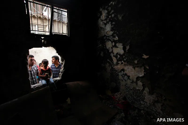 Palestinians look through the window of burnt house after a candle caused a fire at the al-Hendi family's home at the al-Shati refugee camp in Gaza City on May 7, 2016. Photo by Ashraf Amra