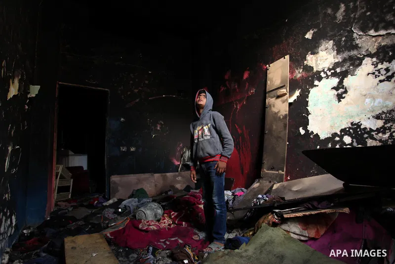 A Palestinian boy looks at the charred walls of a house after a candle caused a fire at the al-Hendi family's home at the al-Shati refugee camp in Gaza City on May 7, 2016. Photo by Ashraf Amra