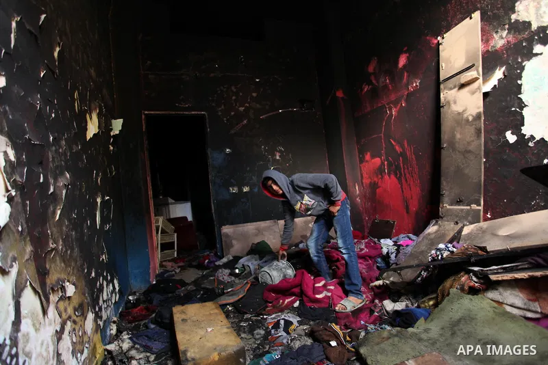 A Palestinian boy collects items from the burnt inside of a house after a candle caused a fire at the al-Hendi family's home at the al-Shati refugee camp in Gaza City on May 7, 2016. Photo by Ashraf Amra