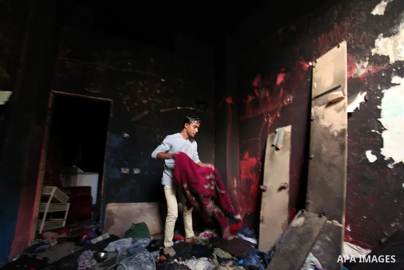 A Palestinian boy collects items from the burnt inside of a house after a candle caused a fire at the al-Hendi family's home at the al-Shati refugee camp in Gaza City on May 7, 2016. Photo by Ashraf Amra