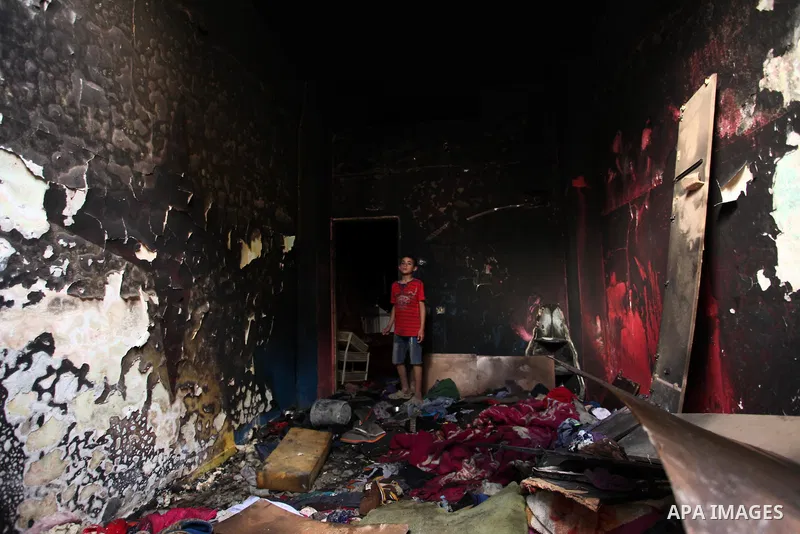 A Palestinian boy looks at the charred walls of a house after a candle caused a fire at the al-Hendi family's home at the al-Shati refugee camp in Gaza City on May 7, 2016. Photo by Ashraf Amra