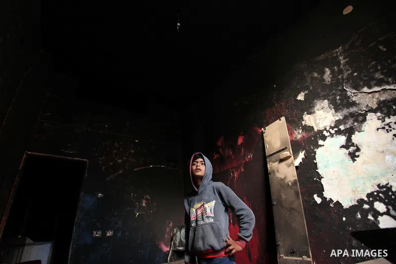 A Palestinian boy looks at the charred walls of a house after a candle caused a fire at the al-Hendi family's home at the al-Shati refugee camp in Gaza City on May 7, 2016. Photo by Ashraf Amra