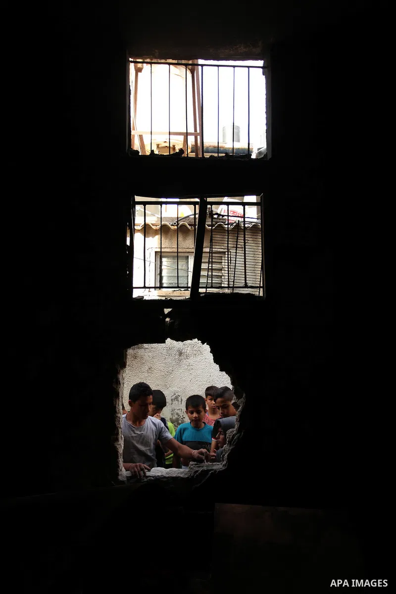 Palestinian children look through the window of burnt house after a candle caused a fire at the al-Hendi family's home at the al-Shati refugee camp in Gaza City on May 7, 2016. Photo by Ashraf Amra