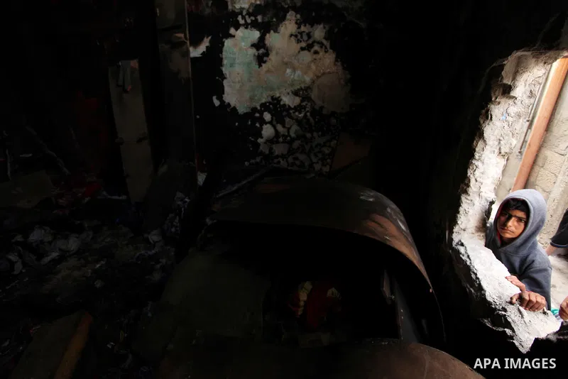 A Palestinian boy looks through the window of burnt house after a candle caused a fire at the al-Hendi family's home at the al-Shati refugee camp in Gaza City on May 7, 2016. Photo by Ashraf Amra