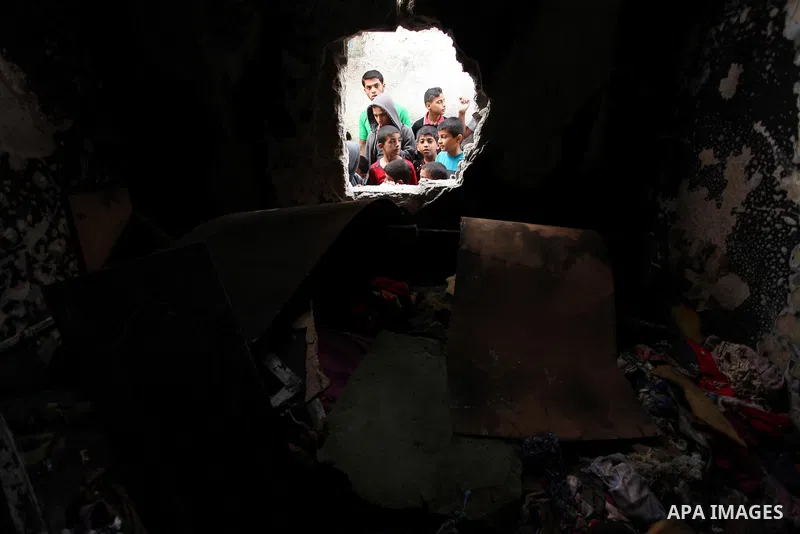 Palestinian children look through the window of burnt house after a candle caused a fire at the al-Hendi family's home at the al-Shati refugee camp in Gaza City on May 7, 2016. Photo by Ashraf Amra