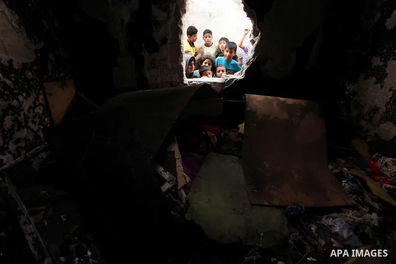 Palestinian children look through the window of burnt house after a candle caused a fire at the al-Hendi family's home at the al-Shati refugee camp in Gaza City on May 7, 2016. Photo by Ashraf Amra