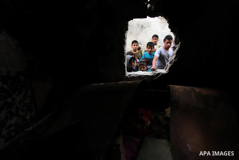 Palestinian children look through the window of burnt house after a candle caused a fire at the al-Hendi family's home at the al-Shati refugee camp in Gaza City on May 7, 2016. Photo by Ashraf Amra