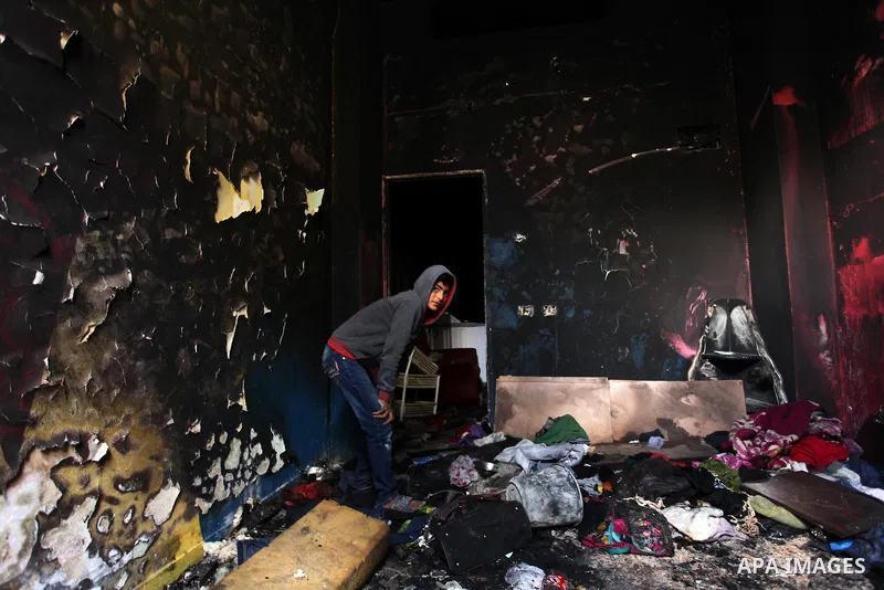 A Palestinian boy collects items from the burnt inside of a house after a candle caused a fire at the al-Hendi family's home at the al-Shati refugee camp in Gaza City on May 7, 2016. Photo by Ashraf Amra