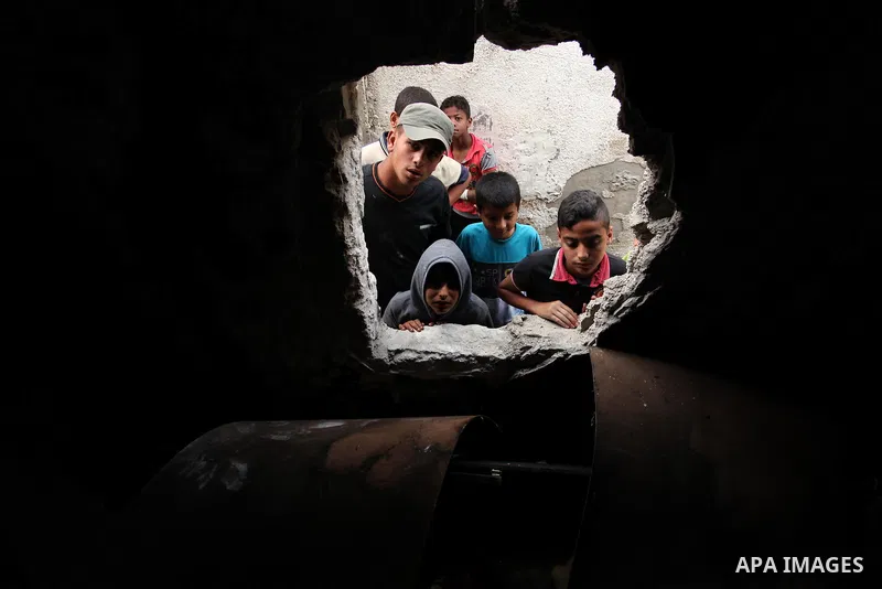 Palestinian children look through the window of burnt house after a candle caused a fire at the al-Hendi family's home at the al-Shati refugee camp in Gaza City on May 7, 2016. Photo by Ashraf Amra