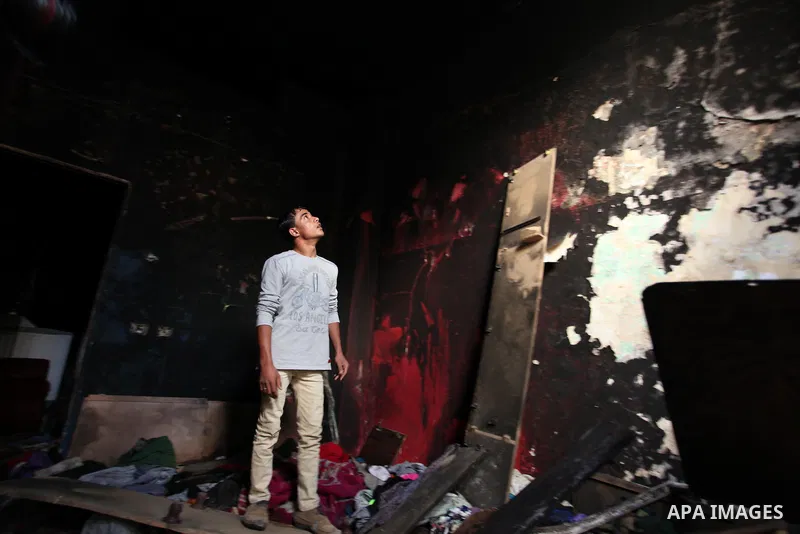 A Palestinian man looks at the charred walls of a house after a candle caused a fire at the al-Hendi family's home at the al-Shati refugee camp in Gaza City on May 7, 2016. Photo by Ashraf Amra
