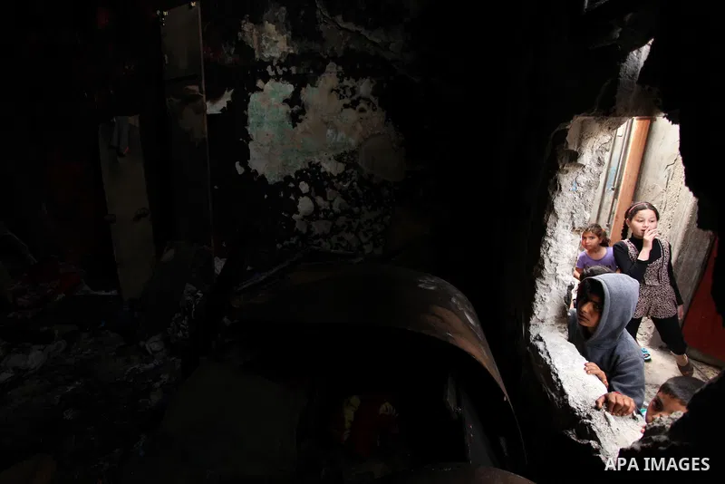 Palestinian children look through the window of burnt house after a candle caused a fire at the al-Hendi family's home at the al-Shati refugee camp in Gaza City on May 7, 2016. Photo by Ashraf Amra