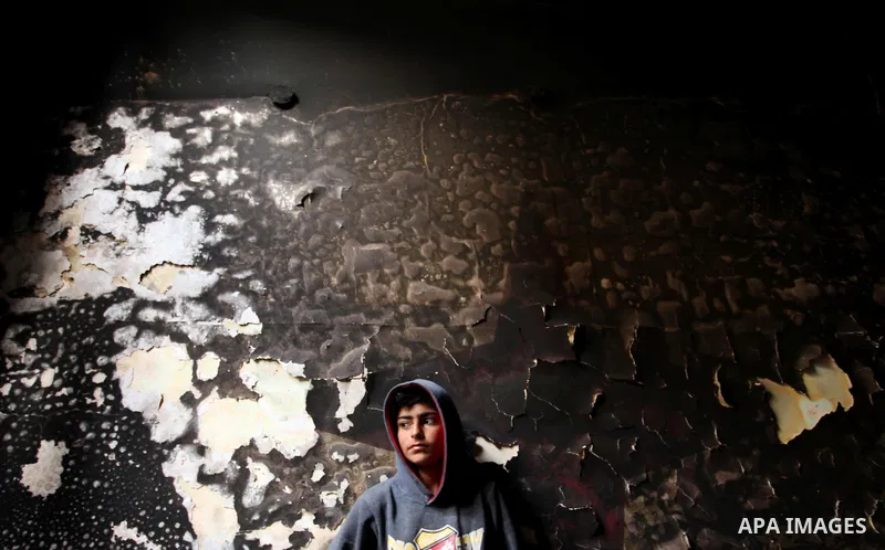 A Palestinian boy looks at the charred walls of a house after a candle caused a fire at the al-Hendi family's home at the al-Shati refugee camp in Gaza City on May 7, 2016. Photo by Ashraf Amra