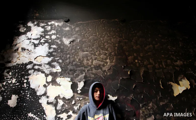 A Palestinian boy looks at the charred walls of a house after a candle caused a fire at the al-Hendi family's home at the al-Shati refugee camp in Gaza City on May 7, 2016. Photo by Ashraf Amra