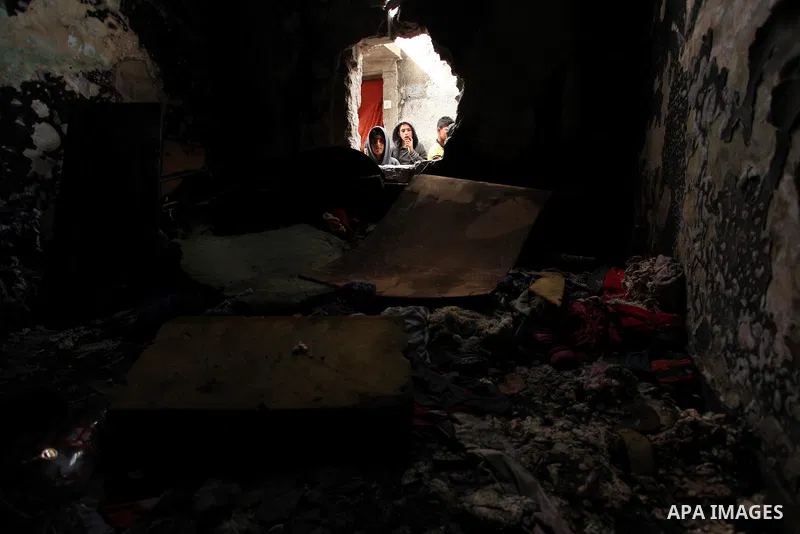 Palestinian children look through the window of burnt house after a candle caused a fire at the al-Hendi family's home at the al-Shati refugee camp in Gaza City on May 7, 2016. Photo by Ashraf Amra