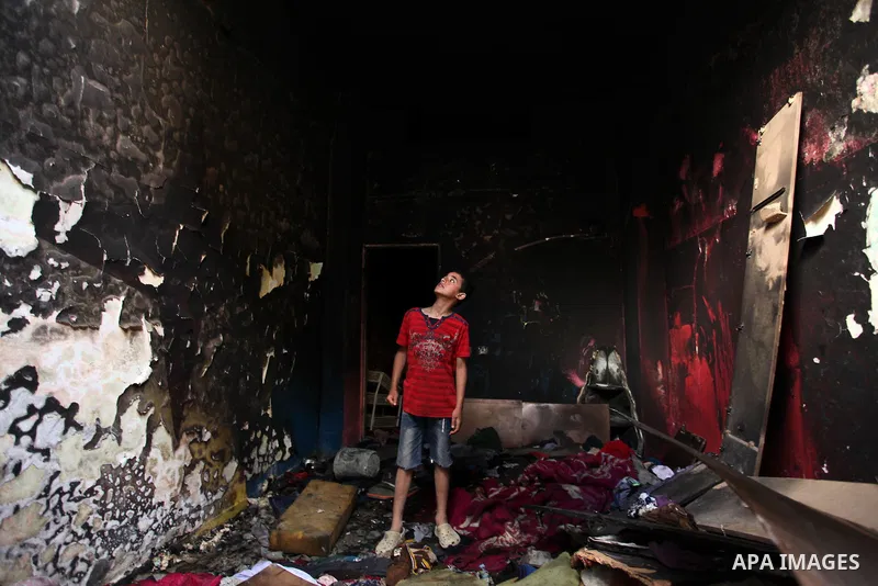 A Palestinian boy looks at the charred walls of a house after a candle caused a fire at the al-Hendi family's home at the al-Shati refugee camp in Gaza City on May 7, 2016. Photo by Ashraf Amra