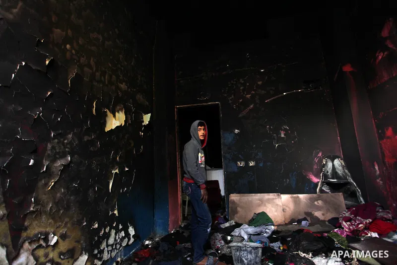 A Palestinian boy looks at the charred walls of a house after a candle caused a fire at the al-Hendi family's home at the al-Shati refugee camp in Gaza City on May 7, 2016. Photo by Ashraf Amra