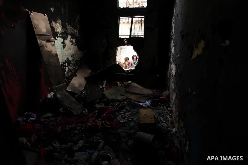 Palestinian children look through the window of burnt house after a candle caused a fire at the al-Hendi family's home at the al-Shati refugee camp in Gaza City on May 7, 2016. Photo by Ashraf Amra