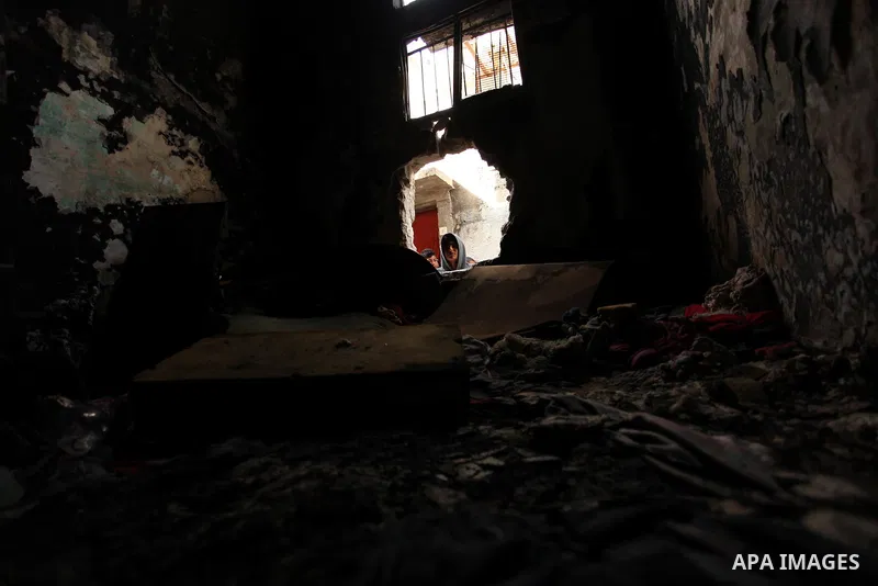A Palestinian boy looks through the window of burnt house after a candle caused a fire at the al-Hendi family's home at the al-Shati refugee camp in Gaza City on May 7, 2016. Photo by Ashraf Amra