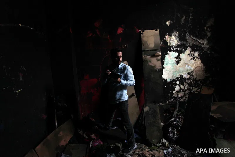 A Palestinian photographer take a photo for a torched house of al-Hendi family's after a candle caused a fire at the their house at the al-Shati refugee camp in Gaza City on May 7, 2016. Photo by Ashraf Amra