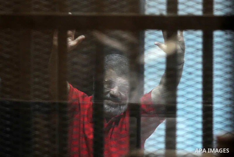 Egypt's ousted Islamist president Mohamed Morsi, wearing a red uniform, gestures from behind the defendant's bars during his trial at the police academy in Cairo on May 7, 2016. An Egyptian court recommended death senten...