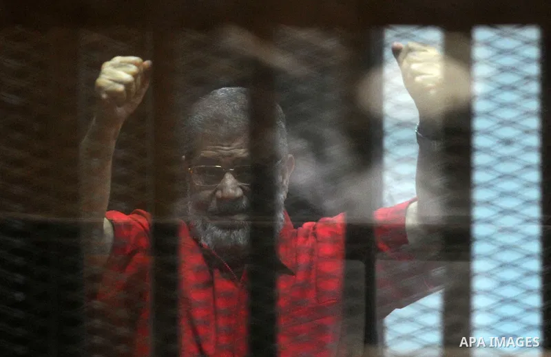 Egypt's ousted Islamist president Mohamed Morsi, wearing a red uniform, gestures from behind the defendant's bars during his trial at the police academy in Cairo on May 7, 2016. An Egyptian court recommended death senten...