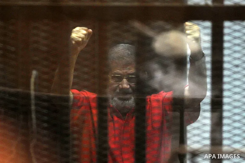Egypt's ousted Islamist president Mohamed Morsi, wearing a red uniform, gestures from behind the defendant's bars during his trial at the police academy in Cairo on May 7, 2016. An Egyptian court recommended death senten...