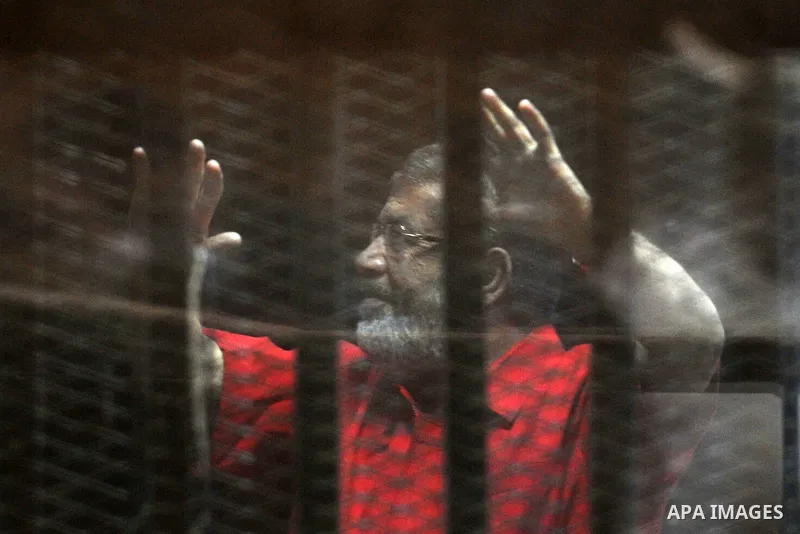 Egypt's ousted Islamist president Mohamed Morsi, wearing a red uniform, gestures from behind the defendant's bars during his trial at the police academy in Cairo on May 7, 2016. An Egyptian court recommended death senten...