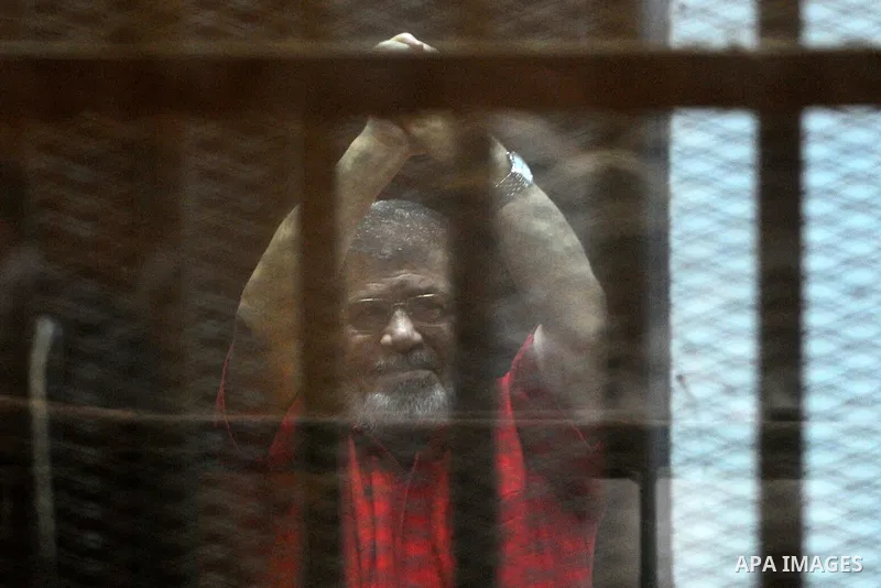 Egypt's ousted Islamist president Mohamed Morsi, wearing a red uniform, gestures from behind the defendant's bars during his trial at the police academy in Cairo on May 7, 2016. An Egyptian court recommended death senten...