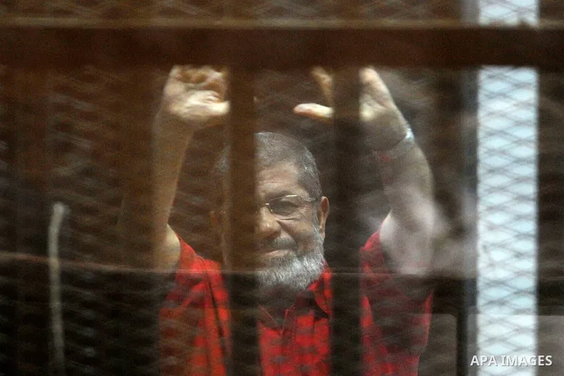 Egypt's ousted Islamist president Mohamed Morsi, wearing a red uniform, gestures from behind the defendant's bars during his trial at the police academy in Cairo on May 7, 2016. An Egyptian court recommended death senten...