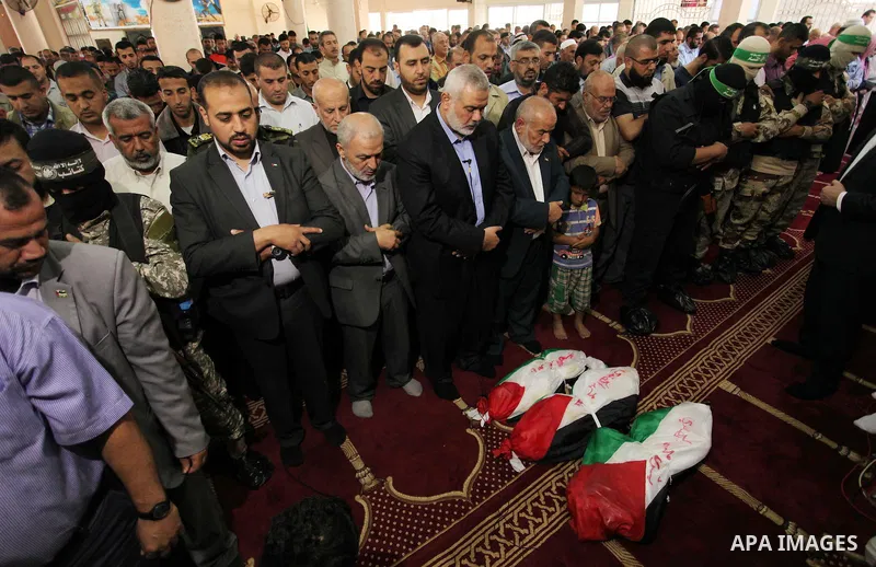 Palestinian mourners pray over the bodies of three children from the al-Hindi family, who died in a fire caused by a candle at the family home during their funeral at the al-Shati refugee camp in Gaza City on May 7, 2016...