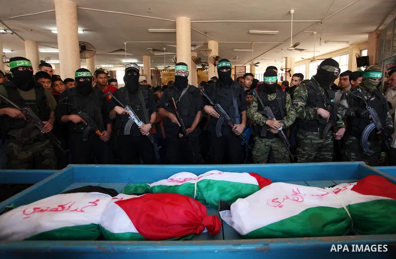Members of the Ezzedine al-Qassam Brigades, the military wing of the Palestinian Islamist movement Hamas, mourn next to the bodies of three children from the al-Hindi family, who died in a fire caused by a candle at the...