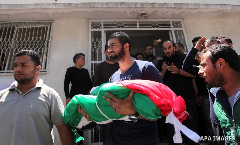 Palestinians carry the bodies of three children from the Abu Hindi family, who died in a fire caused by a candle at the family home, during their funeral at the al-Shati refugee camp in Gaza City on May 7, 2016. Photo by...