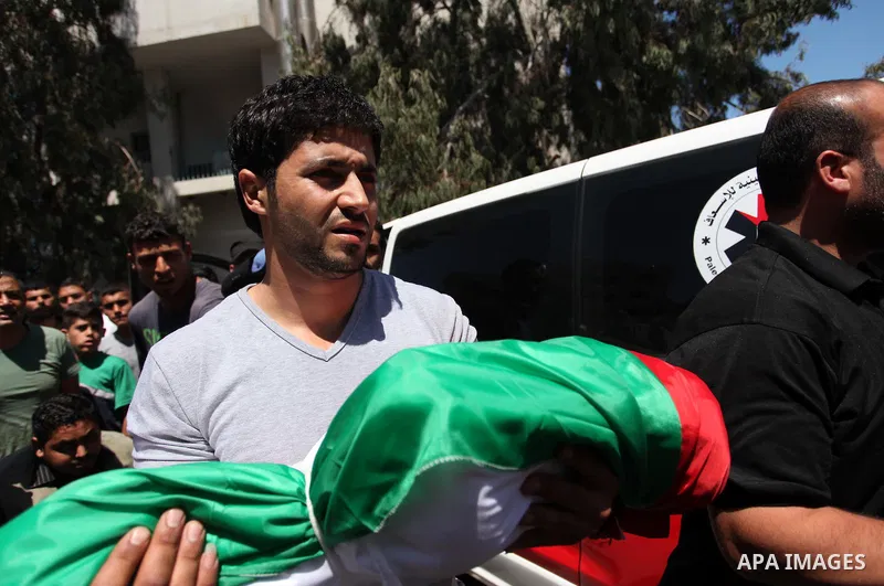 Palestinians carry the bodies of three children from the Abu Hindi family, who died in a fire caused by a candle at the family home, during their funeral at the al-Shati refugee camp in Gaza City on May 7, 2016. Photo by...