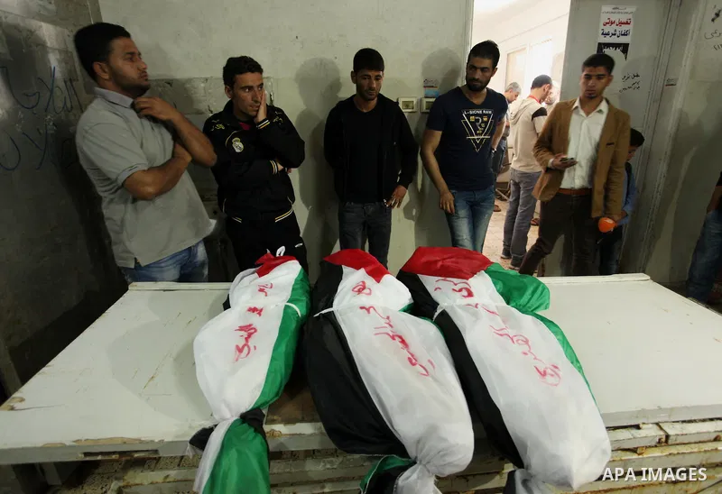 Palestinian relatives of three children from the al-Hindi family who died in a fire caused by a candle at the family home, mourn next to their bodies at al-Shifa hospital in Gaza City on May 7, 2016. Photo by Ashraf Amra