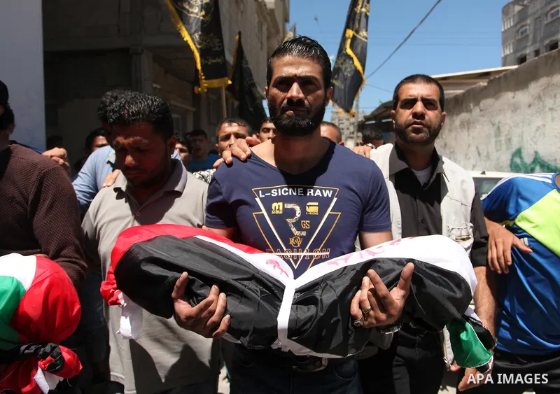 Palestinians carry the bodies of three children from the Abu Hindi family, who died in a fire caused by a candle at the family home, during their funeral at the al-Shati refugee camp in Gaza City on May 7, 2016. Photo by...
