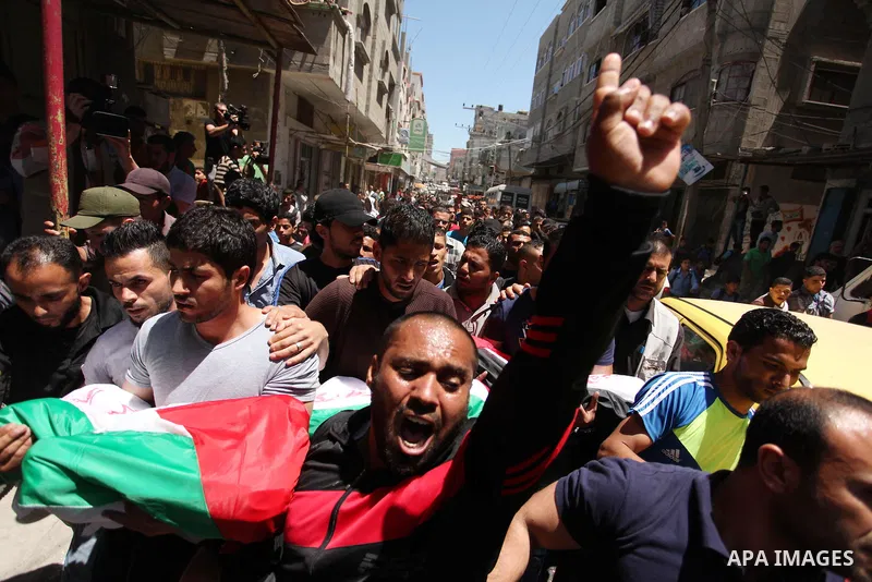 Palestinians carry the bodies of three children from the Abu Hindi family, who died in a fire caused by a candle at the family home, during their funeral at the al-Shati refugee camp in Gaza City on May 7, 2016. Photo by...
