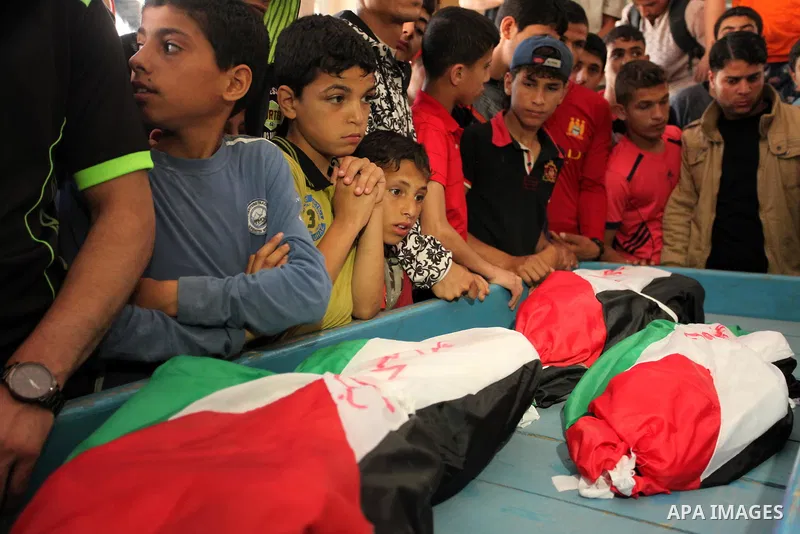 Palestinian children mourn next to the bodies of three boys from the al-Hindi family, who died in a fire caused by a candle at the family home, during their funeral at the al-Shati refugee camp in Gaza City on May 7, 201...