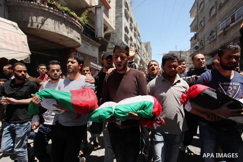 Palestinians carry the bodies of three children from the Abu Hindi family, who died in a fire caused by a candle at the family home, during their funeral at the al-Shati refugee camp in Gaza City on May 7, 2016. Photo by...
