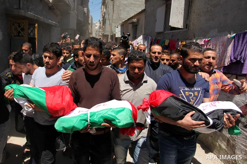 Palestinians carry the bodies of three children from the Abu Hindi family, who died in a fire caused by a candle at the family home, during their funeral at the al-Shati refugee camp in Gaza City on May 7, 2016. Photo by...