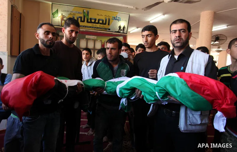 Palestinians carry the bodies of three children from the Abu Hindi family, who died in a fire caused by a candle at the family home, during their funeral at the al-Shati refugee camp in Gaza City on May 7, 2016. Photo by...