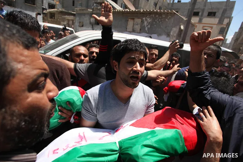 Palestinians carry the bodies of three children from the Abu Hindi family, who died in a fire caused by a candle at the family home, during their funeral at the al-Shati refugee camp in Gaza City on May 7, 2016. Photo by...