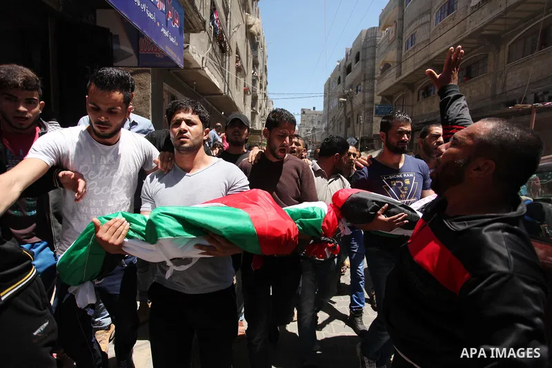 Palestinians carry the bodies of three children from the Abu Hindi family, who died in a fire caused by a candle at the family home, during their funeral at the al-Shati refugee camp in Gaza City on May 7, 2016. Photo by...
