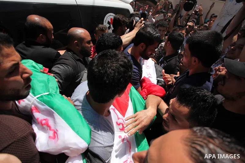 Palestinians carry the bodies of three children from the Abu Hindi family, who died in a fire caused by a candle at the family home, during their funeral at the al-Shati refugee camp in Gaza City on May 7, 2016. Photo by...
