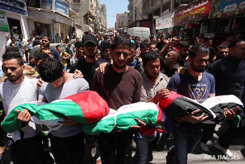 Palestinians carry the bodies of three children from the Abu Hindi family, who died in a fire caused by a candle at the family home, during their funeral at the al-Shati refugee camp in Gaza City on May 7, 2016. Photo by...
