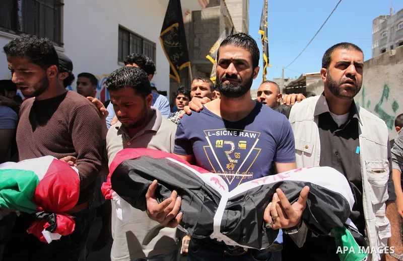 Palestinians carry the bodies of three children from the Abu Hindi family, who died in a fire caused by a candle at the family home, during their funeral at the al-Shati refugee camp in Gaza City on May 7, 2016. Photo by...