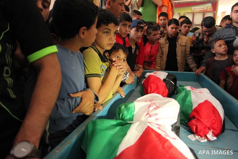 Palestinian children mourn next to the bodies of three boys from the al-Hindi family, who died in a fire caused by a candle at the family home, during their funeral at the al-Shati refugee camp in Gaza City on May 7, 201...