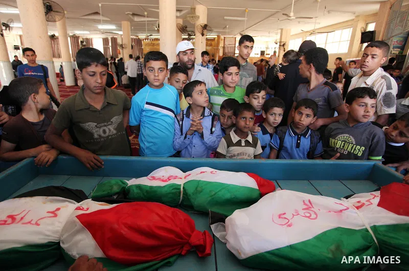 Palestinian children mourn next to the bodies of three boys from the al-Hindi family, who died in a fire caused by a candle at the family home, during their funeral at the al-Shati refugee camp in Gaza City on May 7, 201...